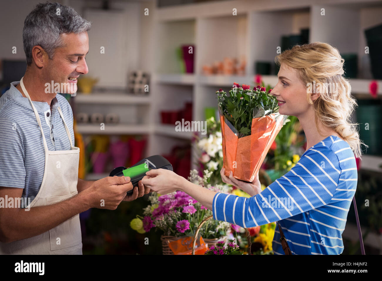 Donna di effettuare il pagamento con la sua carta di credito per un fioraio Foto Stock