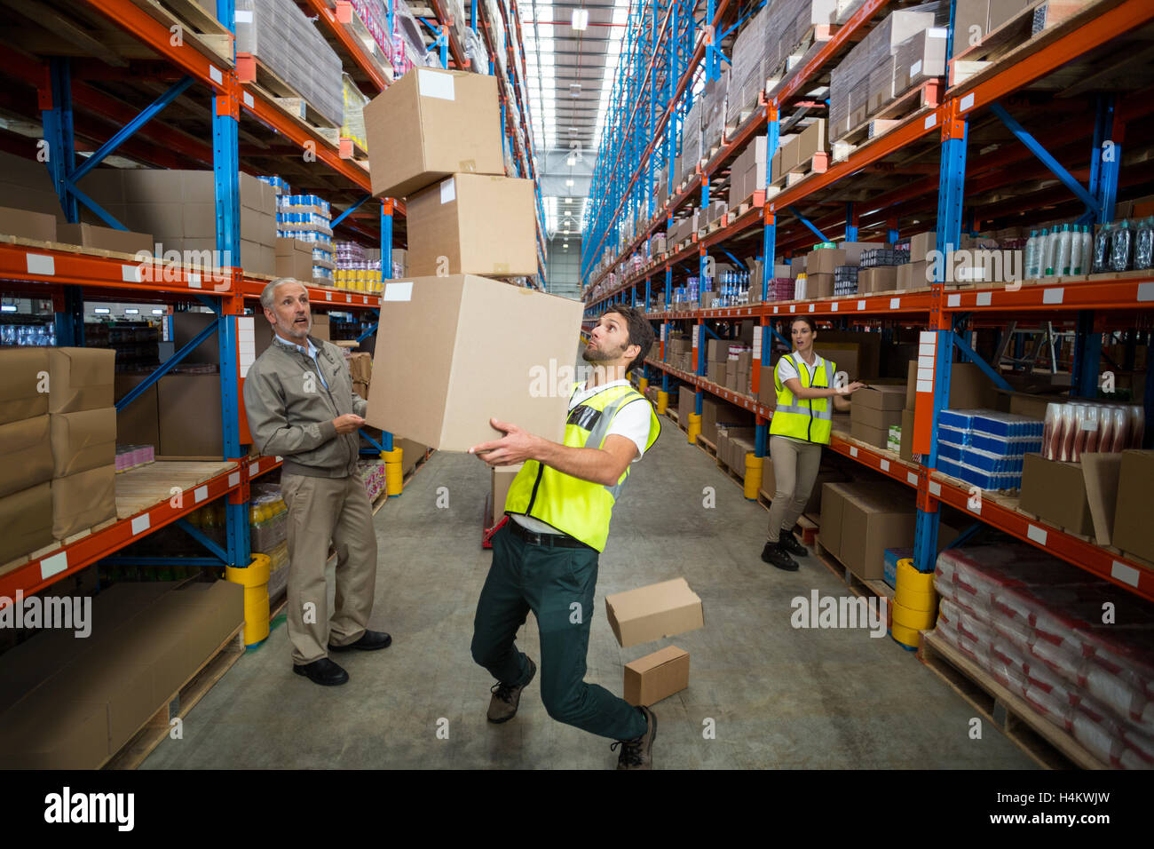 Lavoratore di perdere il suo equilibrio durante il trasporto di scatole di cartone Foto Stock