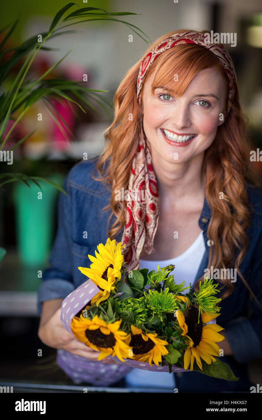 Donna sorridente fioraio azienda mazzetto di fiori Foto Stock