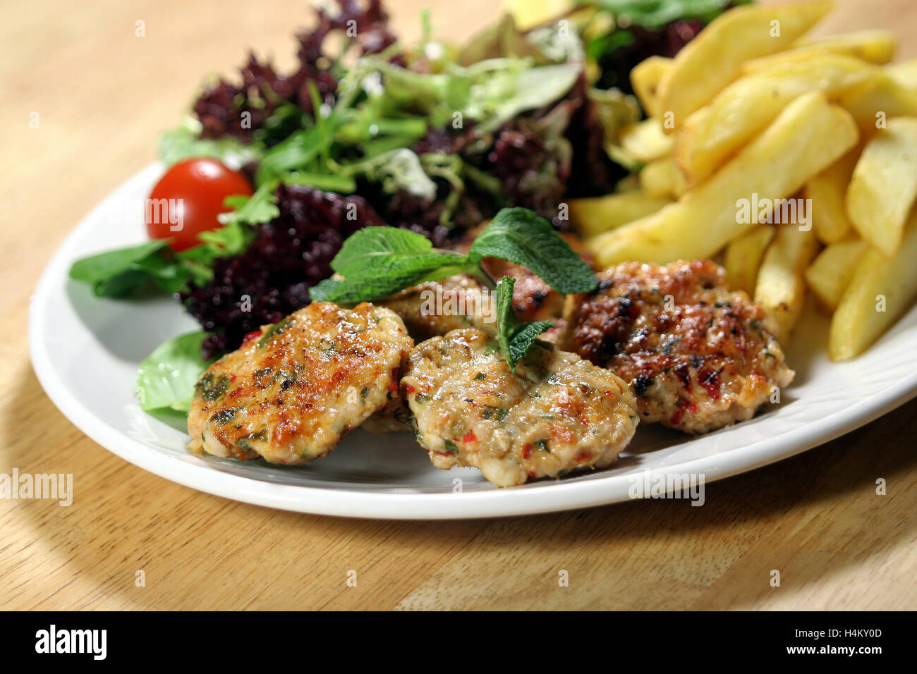 Pollo grigliato servito con le polpette con patate fritte e insalata mista Foto Stock