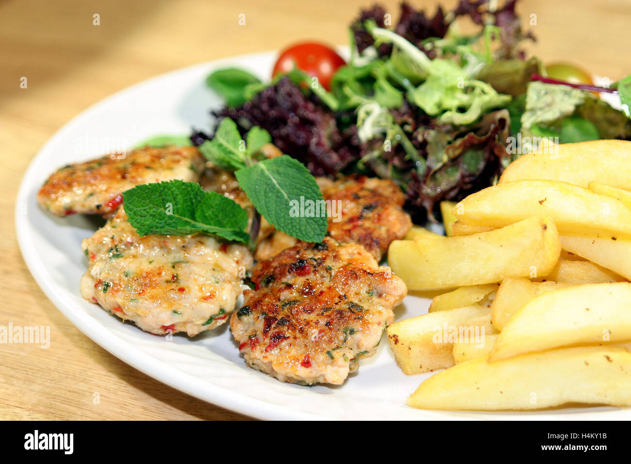 Pollo grigliato servito con le polpette con patate fritte e insalata mista Foto Stock