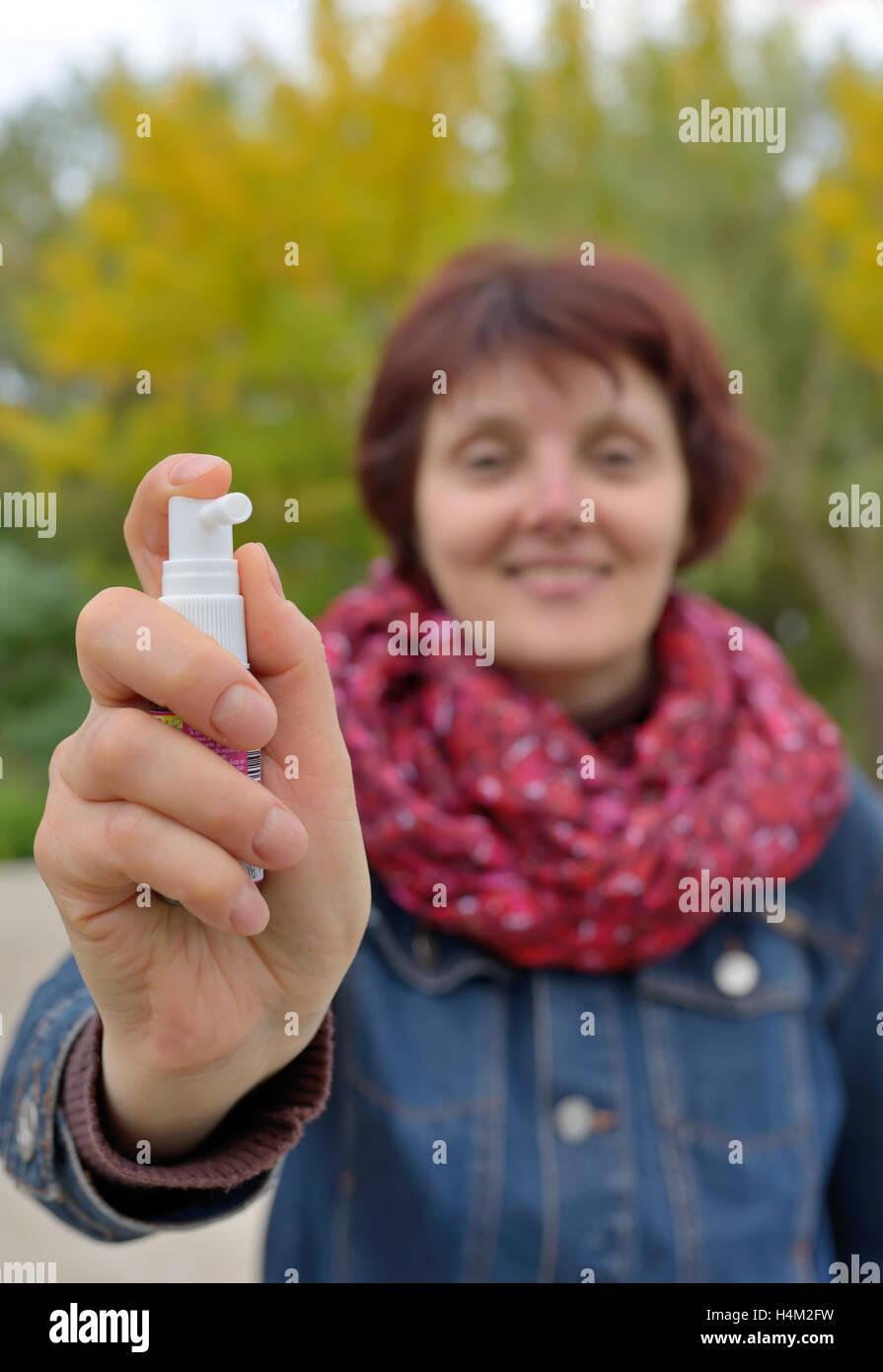 Donna che utilizza spray gola nella stagione fredda Foto Stock