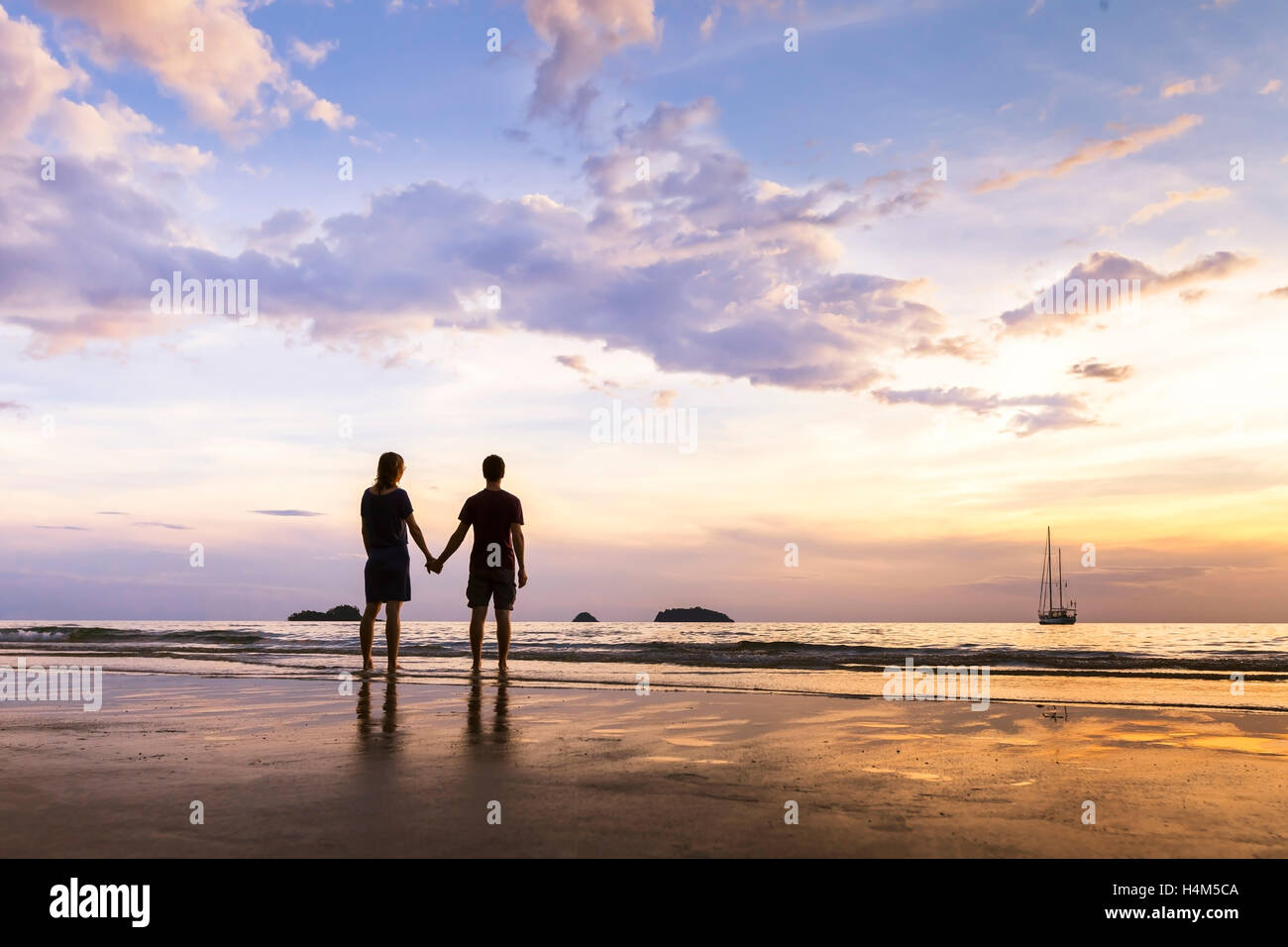 Silhouette di felice coppia avente una romantica passeggiata costiera e vicino al mare in Paradise Island Foto Stock