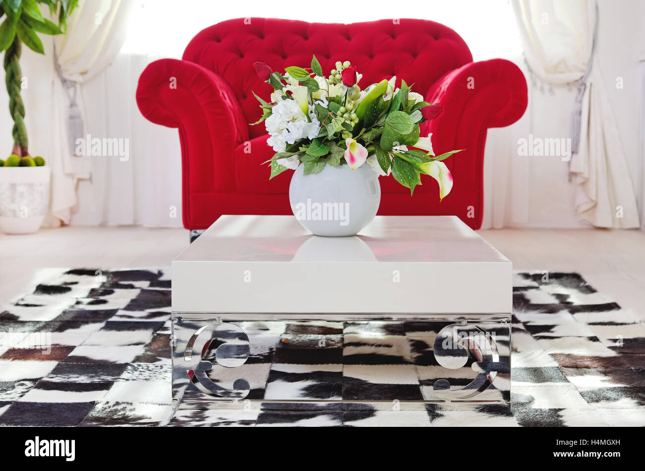 Red classica poltrona in salotto interno vicino a tavolino con fiori Foto Stock