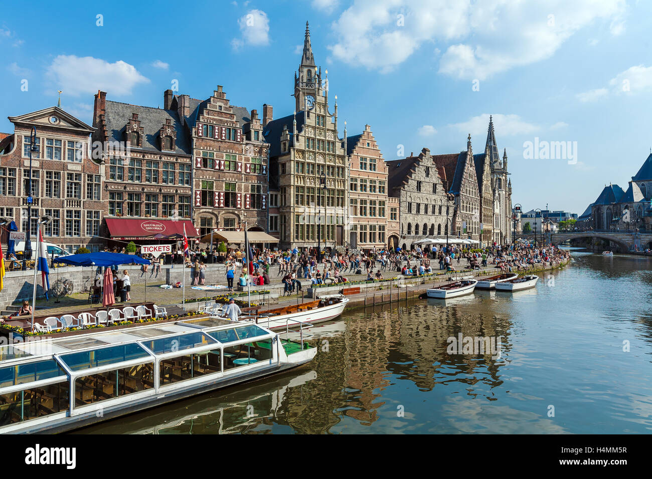 GHENT, Belgio - Aprile 6, 2008: Tour di barche e gli studenti seduti sul lungomare del fiume Leie lungo Graslei street Foto Stock