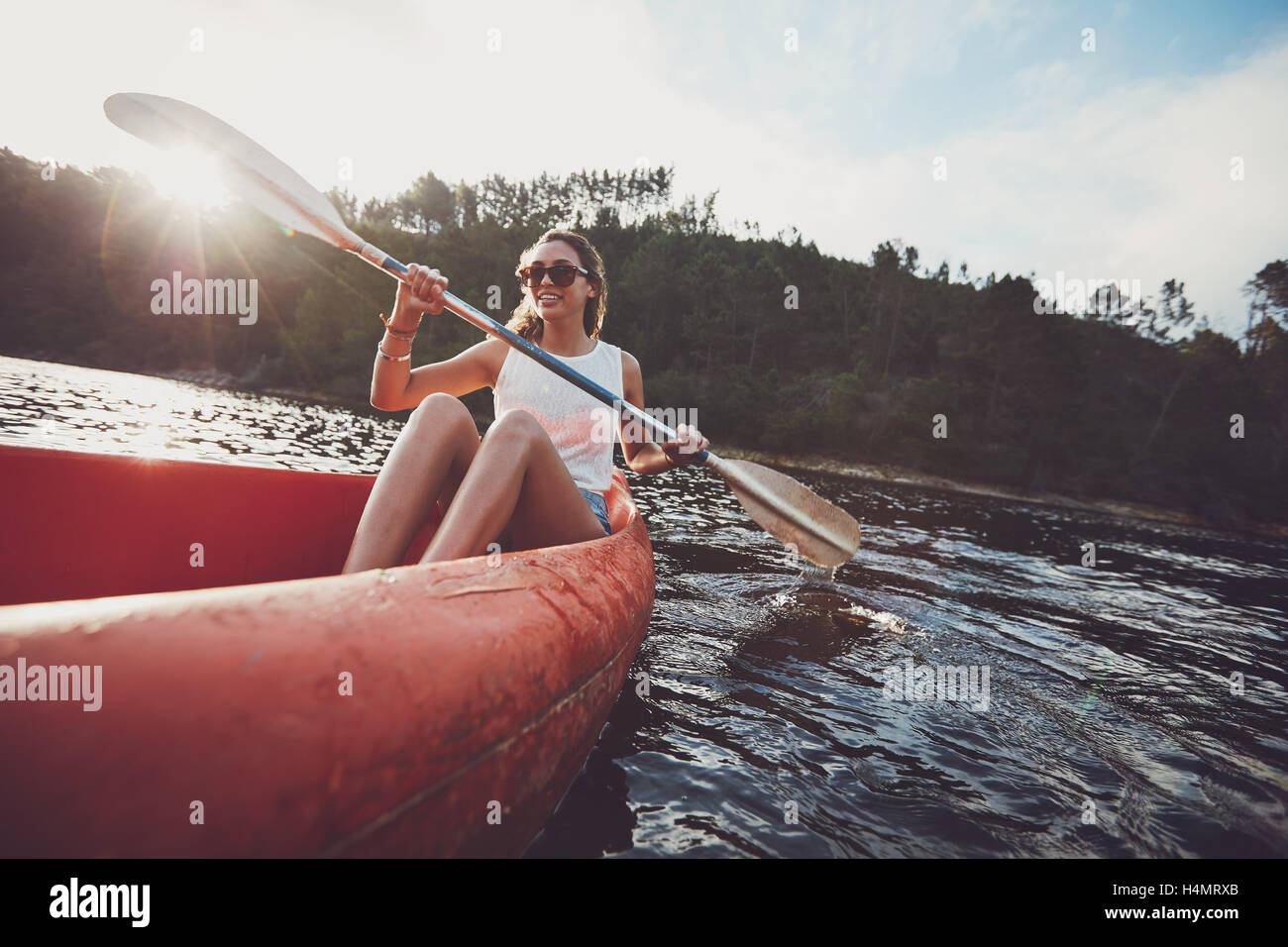Giovane donna canoa in un lago. Donna canoa kayak su un giorno d'estate. Foto Stock