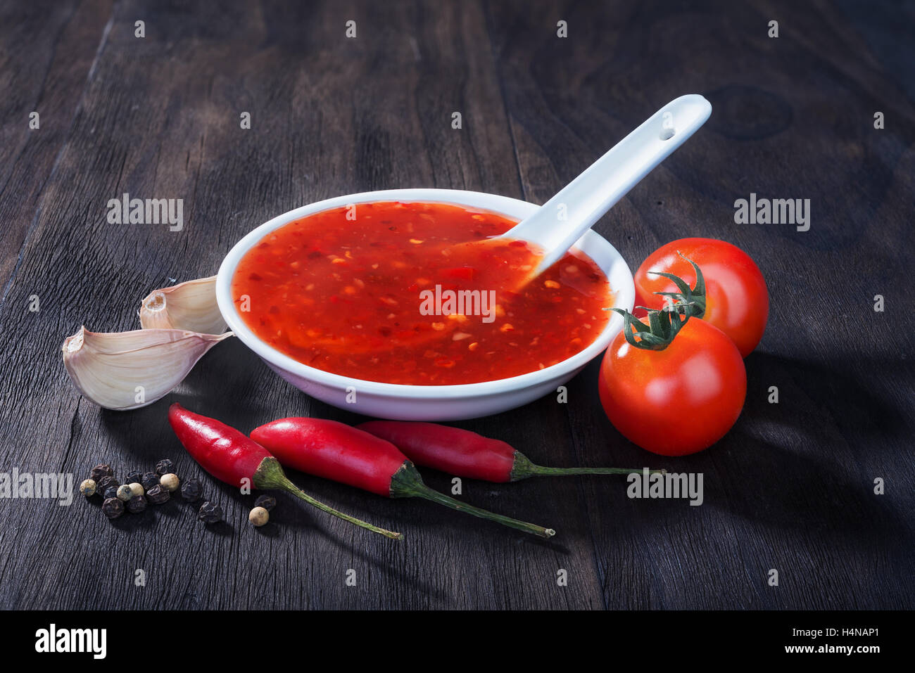 Red Hot Salsa al peperoncino dolce su un vecchio sfondo di legno Foto Stock