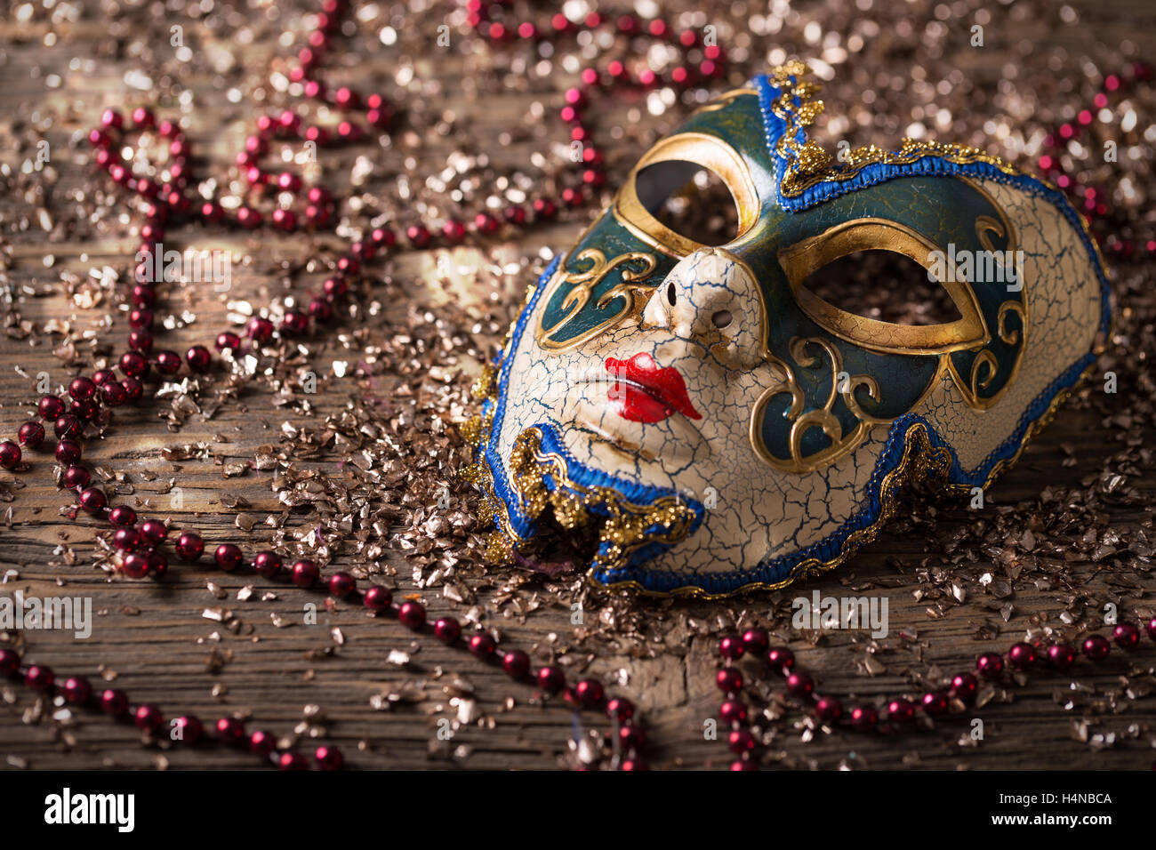 Maschera di carnevale con collana di rosso su sfondo di legno Foto Stock