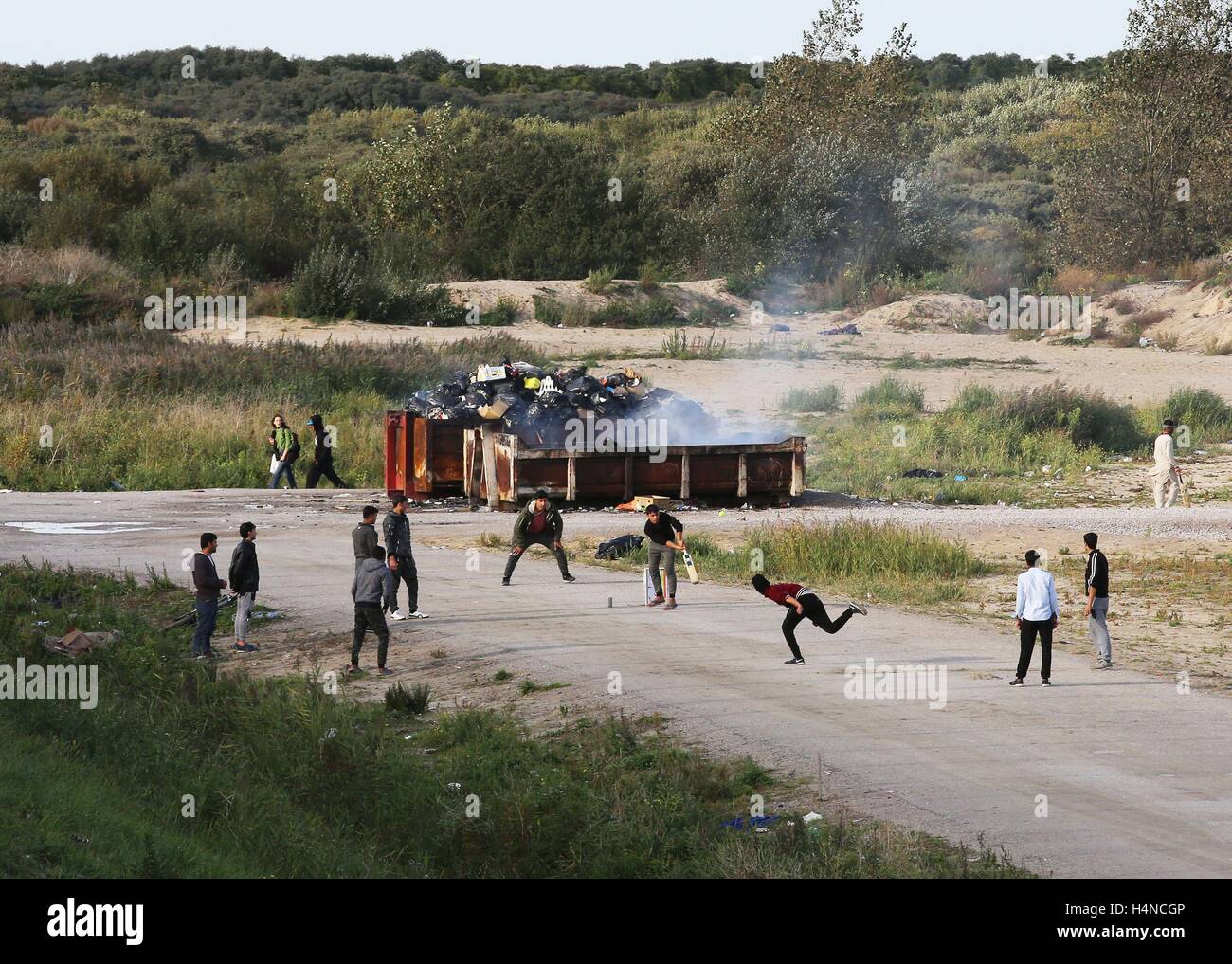 Un gruppo di uomini giocare a cricket nella giungla campo di migranti a Calais, Francia, come i piani sono fatti per cancellare tutto il sito. Stampa foto di associazione. Picture Data: lunedì 17 ottobre, 2016. Bandi di gara è stato pubblicato in negozi in Calais camp noto come 'giungla' avvertenza devono essere evacuato entro due giorni prima della demolizione di edifici di fortuna nella baraccopoli. Il porto della città commissario di polizia Patrick Visser-Bourdon ha visitato la baraccopoli in cui notifica legale dell'ordine di lasciare i negozi è stato pubblicato in francese. Vedere PA storia politica giungla di Calais. Foto di credito dovrebbe leggere: Gareth Fu Foto Stock