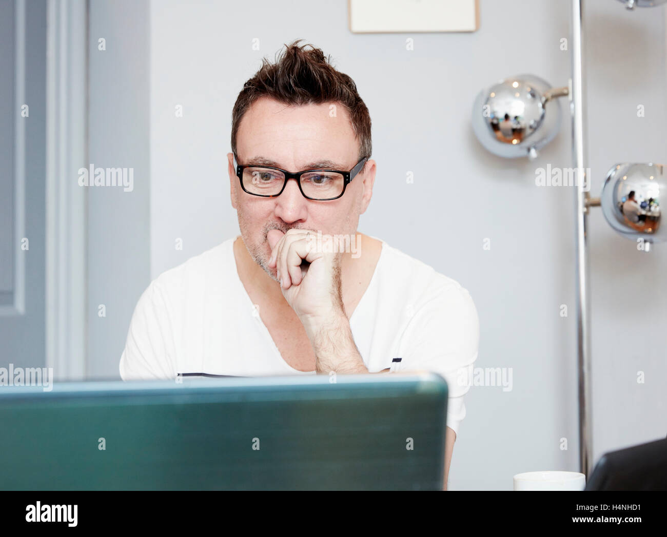 Uomo seduto alla scrivania in ufficio utilizzando un computer portatile. Foto Stock