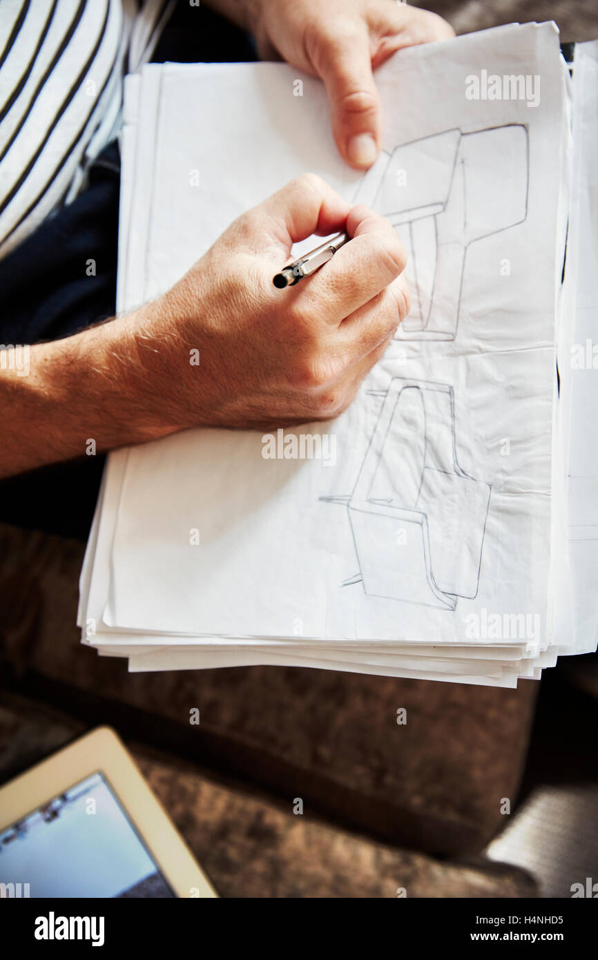Un uomo seduto utilizzando una penna e schizzi di disegno, un progettista al lavoro. Foto Stock