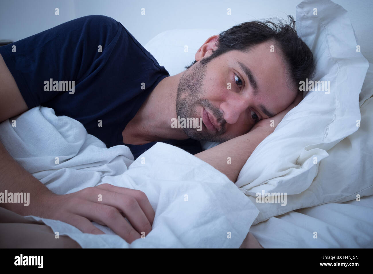 Premuto l Uomo sdraiato sul letto e la sensazione di cattivo Foto Stock
