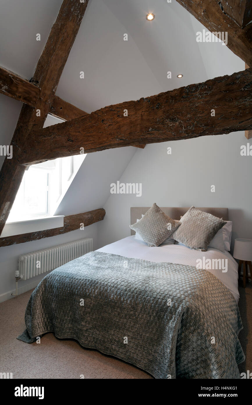 Un accogliente mansarda camera da letto con vecchie travi caratteristiche del periodo Foto Stock