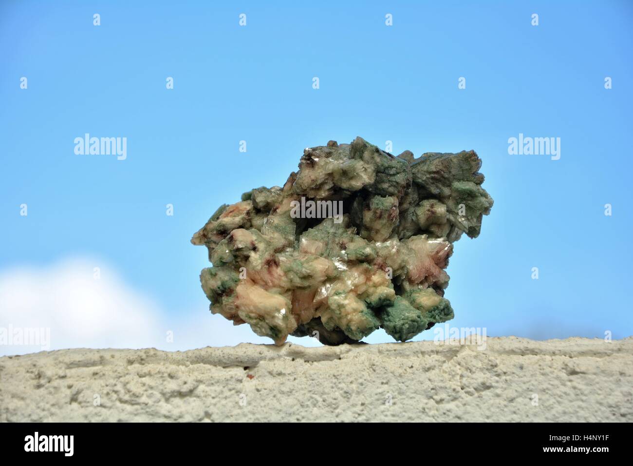 Verde minerale quarzo pietra sul muro bianco contro un cielo blu Foto Stock