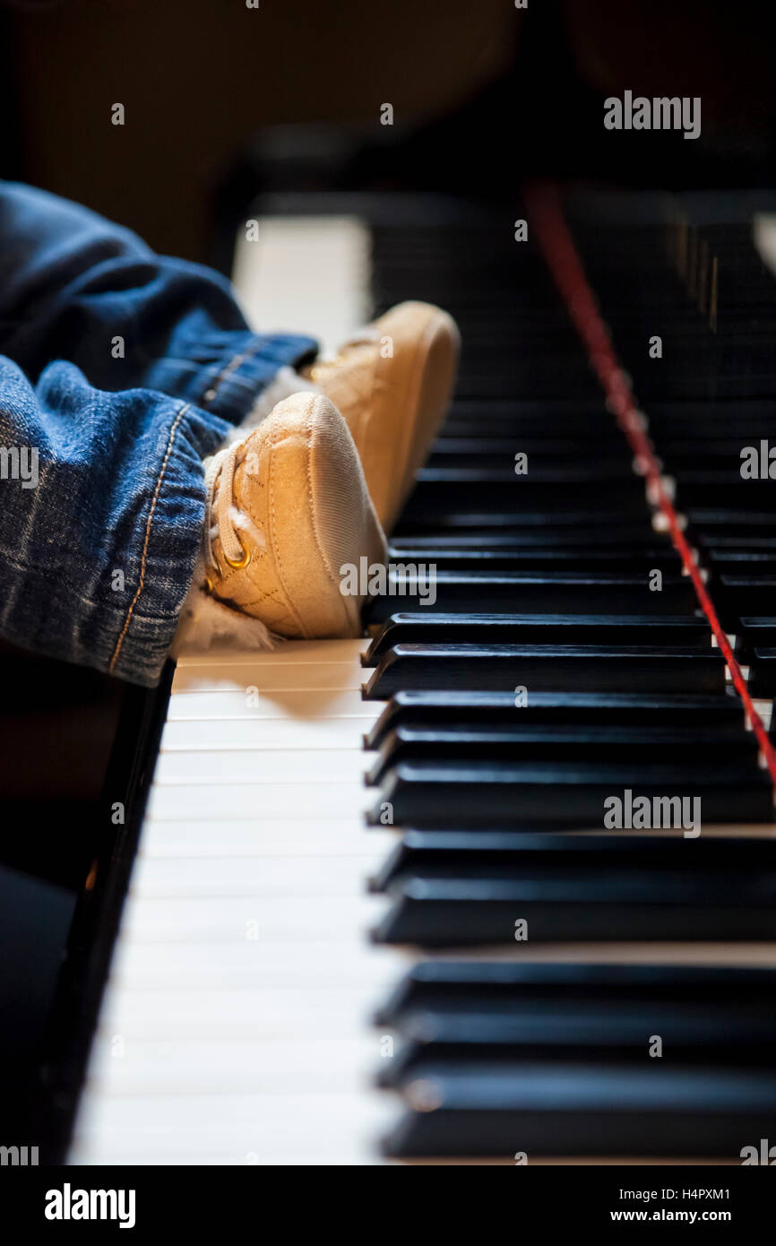 Bambino neonato piedi cercando di giocare di pianoforte classico Foto Stock