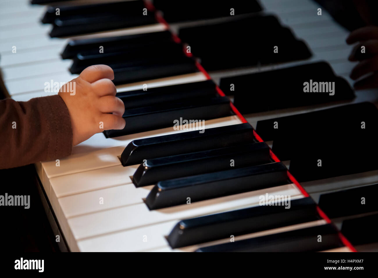 Bambino neonato mano cercando di giocare di pianoforte classico Foto Stock