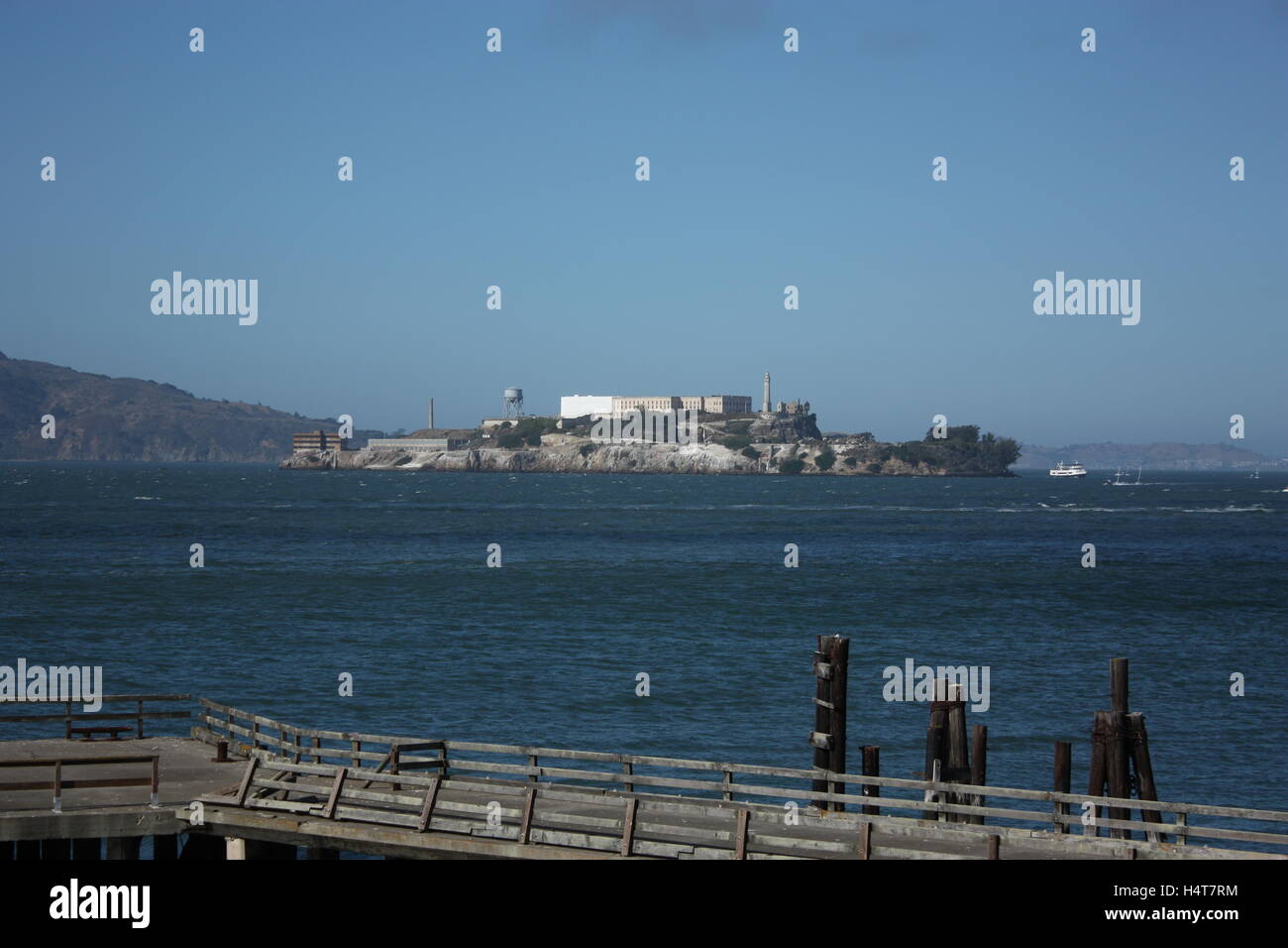 Isola di Alcatraz a distanza con un recinto rotto e il mare in primo piano Foto Stock