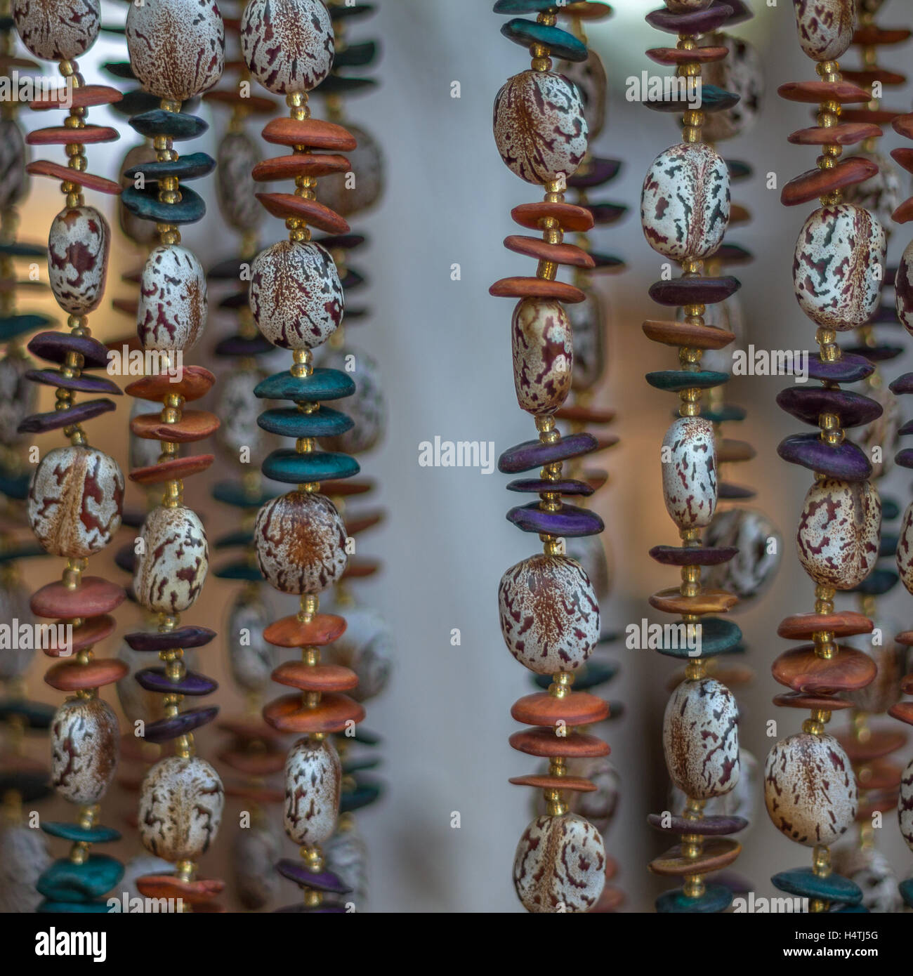 Sei colorate collane di perle appeso verticalmente in un'immagine quadrata prese al mercato di artigianato in Africa australe Foto Stock