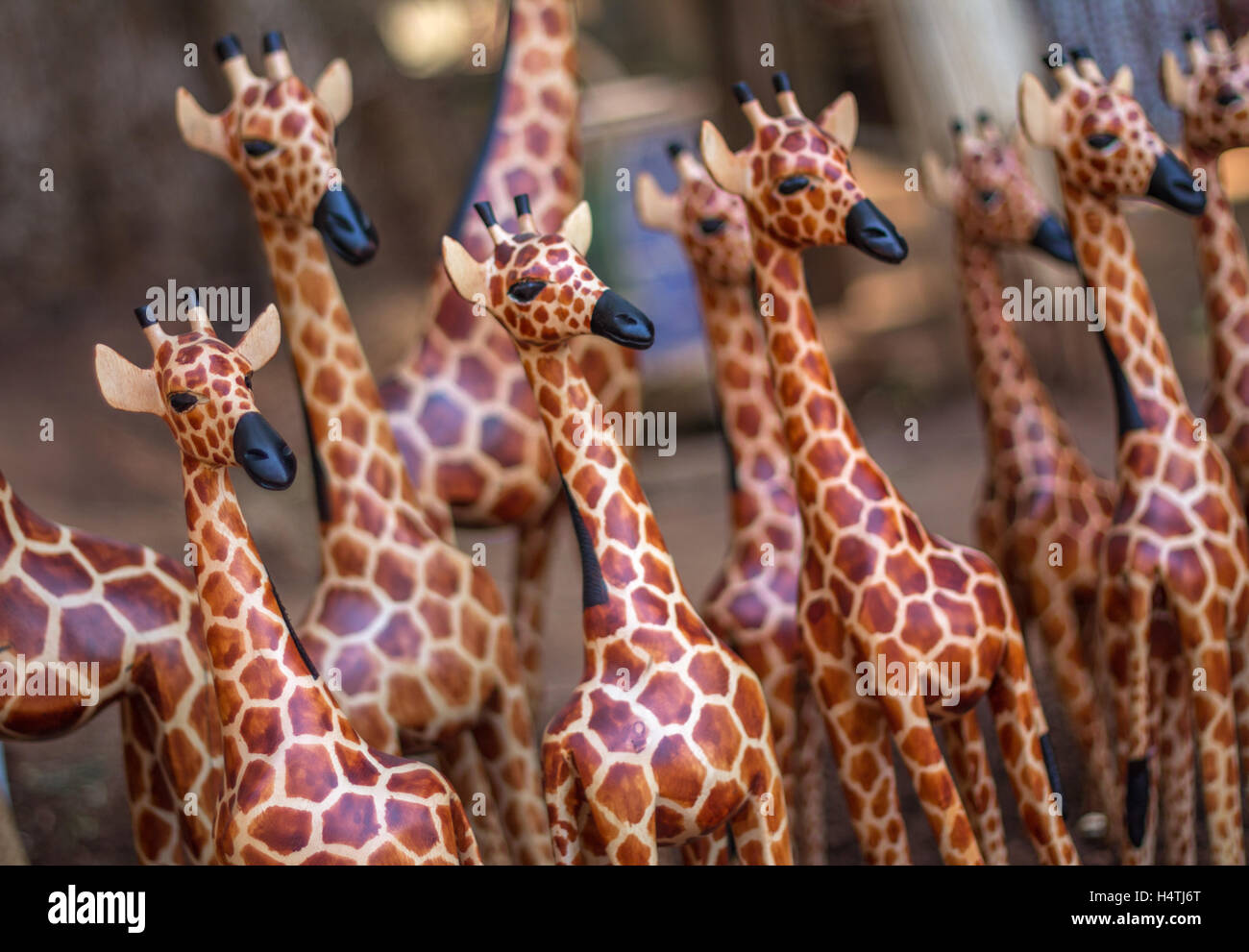 Una giraffa di legno si distingue nella folla di sculture simili poste in diagonale attraverso il telaio per una prospettiva unica Foto Stock