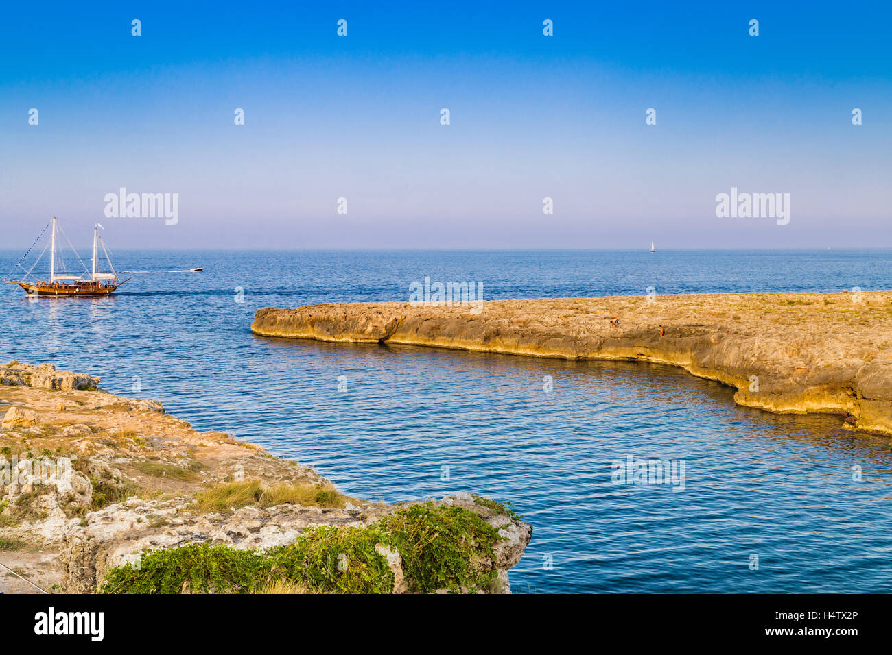 Nave a vela e la costa di Polignano in Puglia in Italia Foto Stock