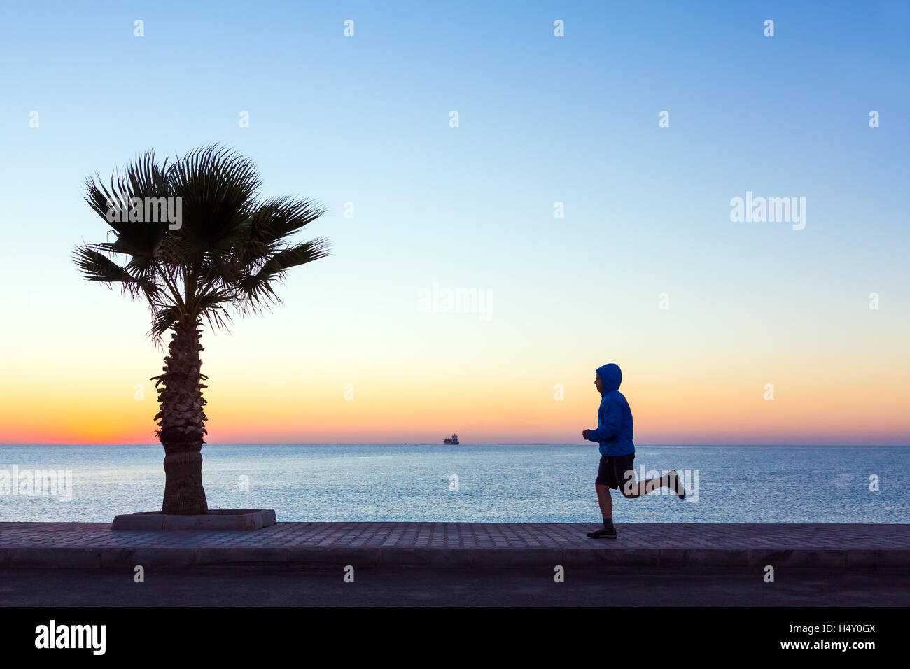 Giovane uomo di jogging sul lungomare rendendo Fitness di mattina Foto Stock
