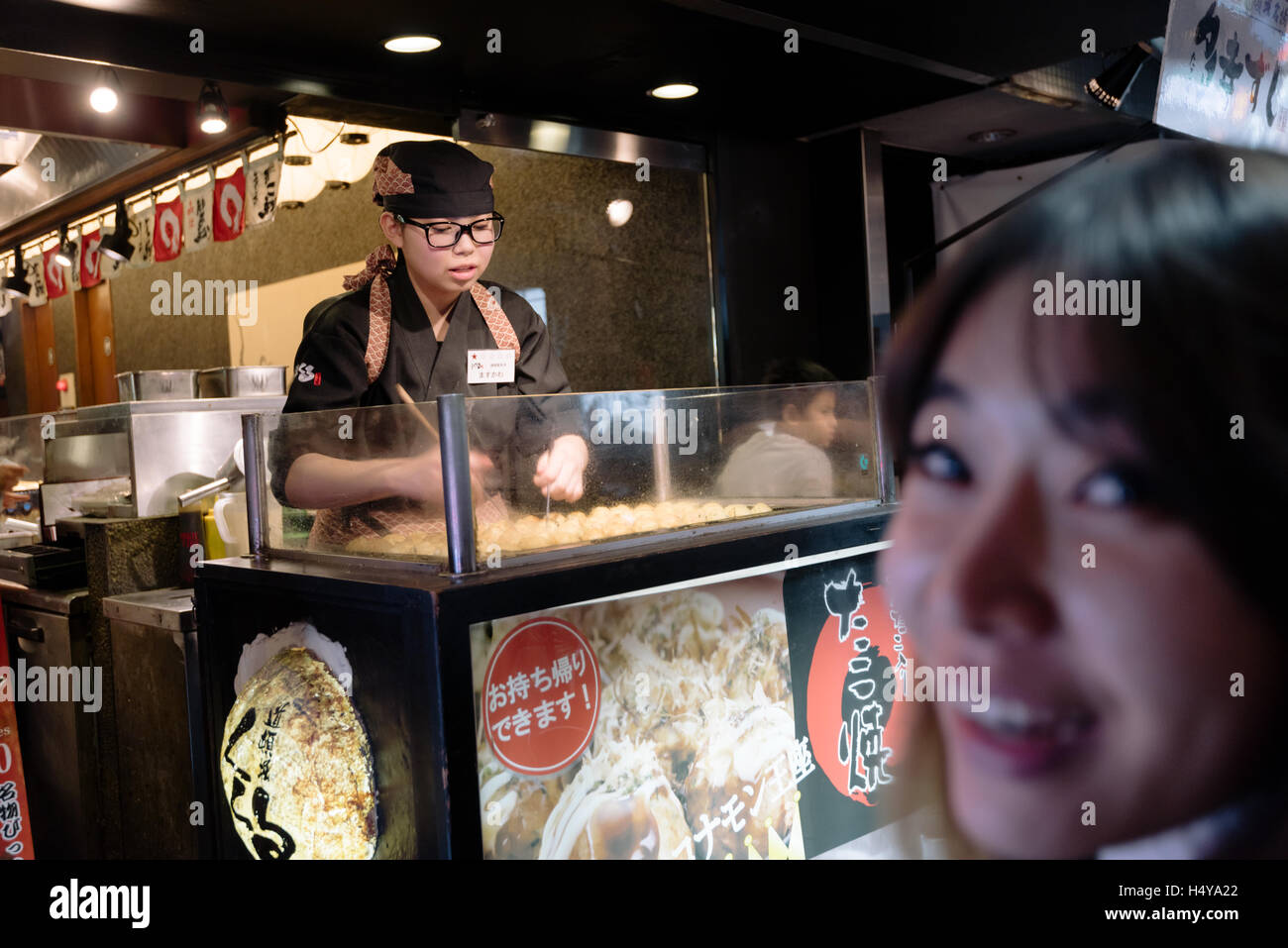 Osaka, Giappone - 29 novembre 2015:Un toruist in attesa per un Takoyaki (polpo palle ) servita presso la strada del quartiere di Dotombori Foto Stock