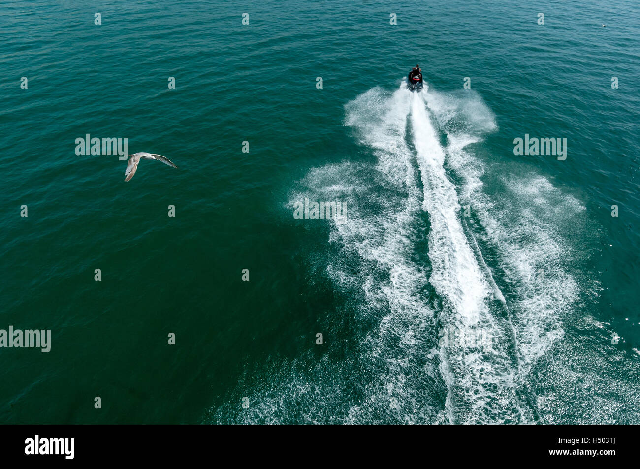 Un uomo su un jet ski tuona sopra l'acqua sulla costa sud dell'Inghilterra Foto Stock