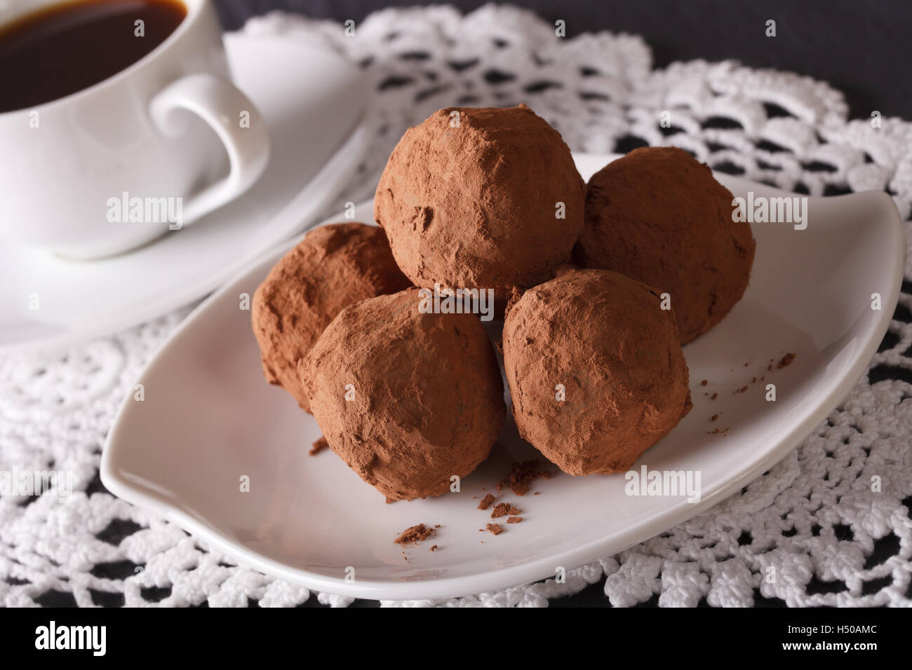 Tartufi di cioccolato su un piattino di close-up e il caffè sul tavolo. Posizione orizzontale Foto Stock