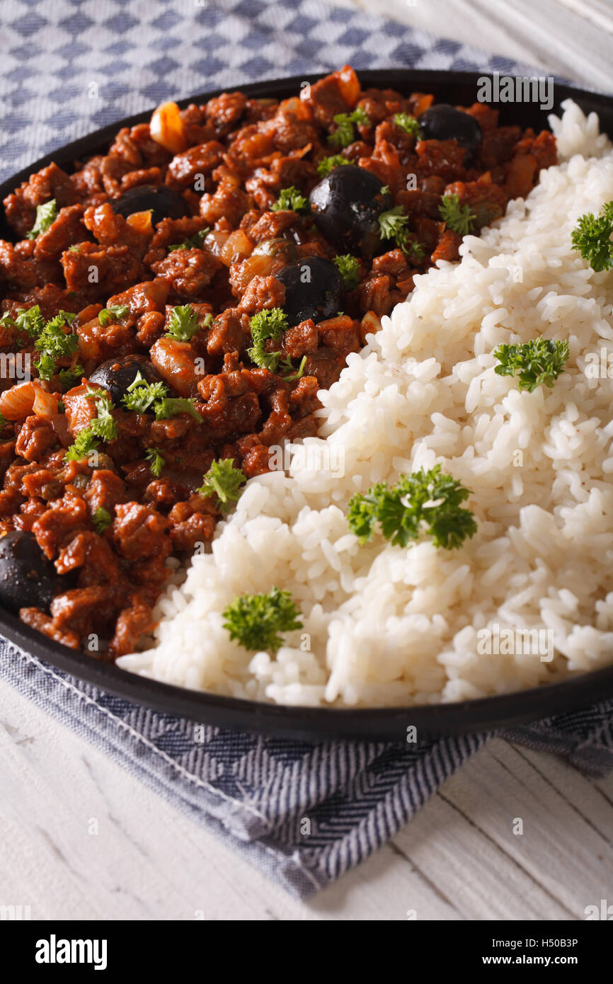 Cibo cubano: Picadillo a la habanera con un lato piatto di riso close-up su una piastra. In verticale Foto Stock