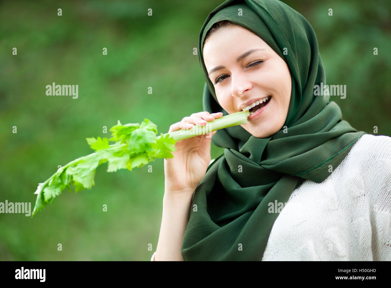 Vegano musulmano donna con velo di mangiare un sedano Foto Stock