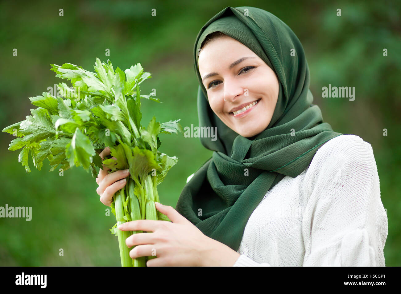Vegano musulmano donna con velo tenendo un sedano Foto Stock