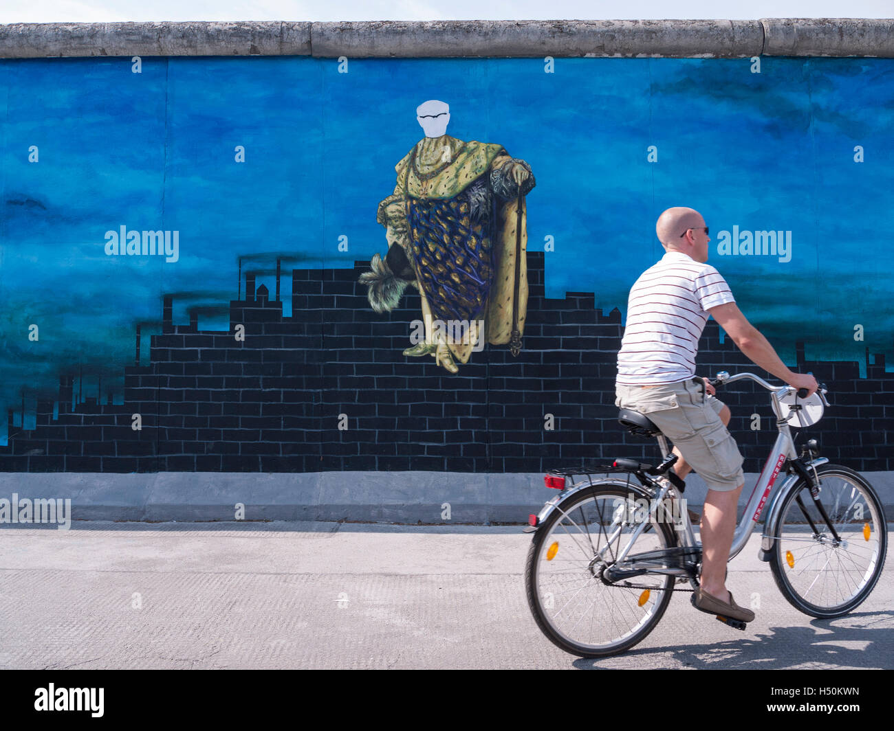Uomo passato cicli di verniciatura di Erich Honecker sulla parete a East Side Gallery parte del vecchio Muro di Berlino a Berlino Germania Foto Stock