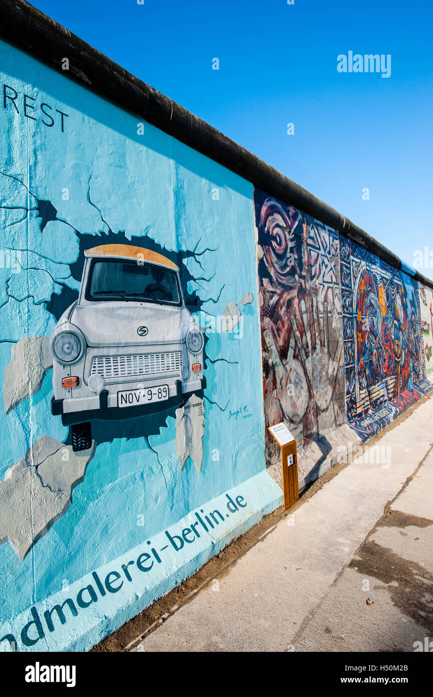 La pittura di Trabant vettura rompere attraverso la parete a East Side Gallery a muro di Berlino in / Friedrichshain Kreuzberg di Berlino Foto Stock