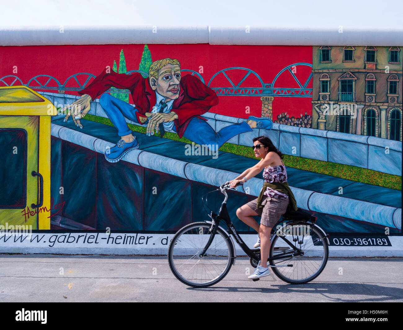 Cicli di donna passato murale sulla parete in corrispondenza di East Side Gallery ex muro di Berlino in / Friedrichshain Kreuzberg Berlino Germania Foto Stock