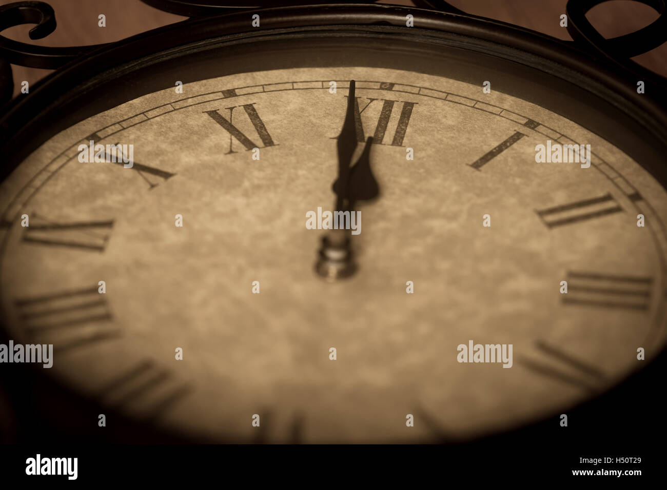 Orologio antico mostra minuto a mezzanotte con la deliberata focus sul numero romano 12 e la profondità di campo del resto fo Foto Stock