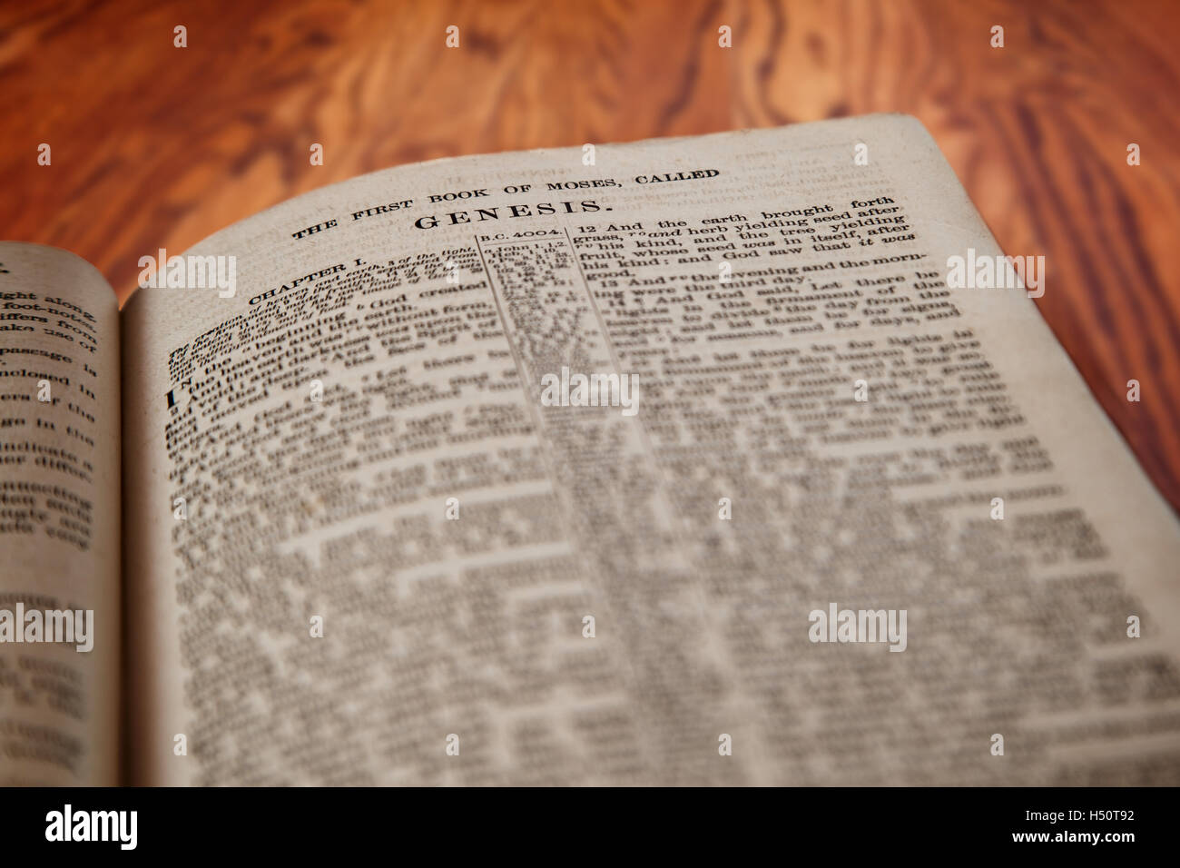 Primo piano di un vecchio Santa Bibbia aperta per il famoso Libro della Genesi su una tavola in legno rustico. La deliberata focus sul titolo. Foto Stock