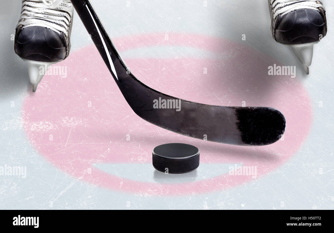 Hockey su ghiaccio faceoff spot mostra stick pronto su puck con pattini del giocatore pronto permanente su ghiaccio. Copia dello spazio. Foto Stock