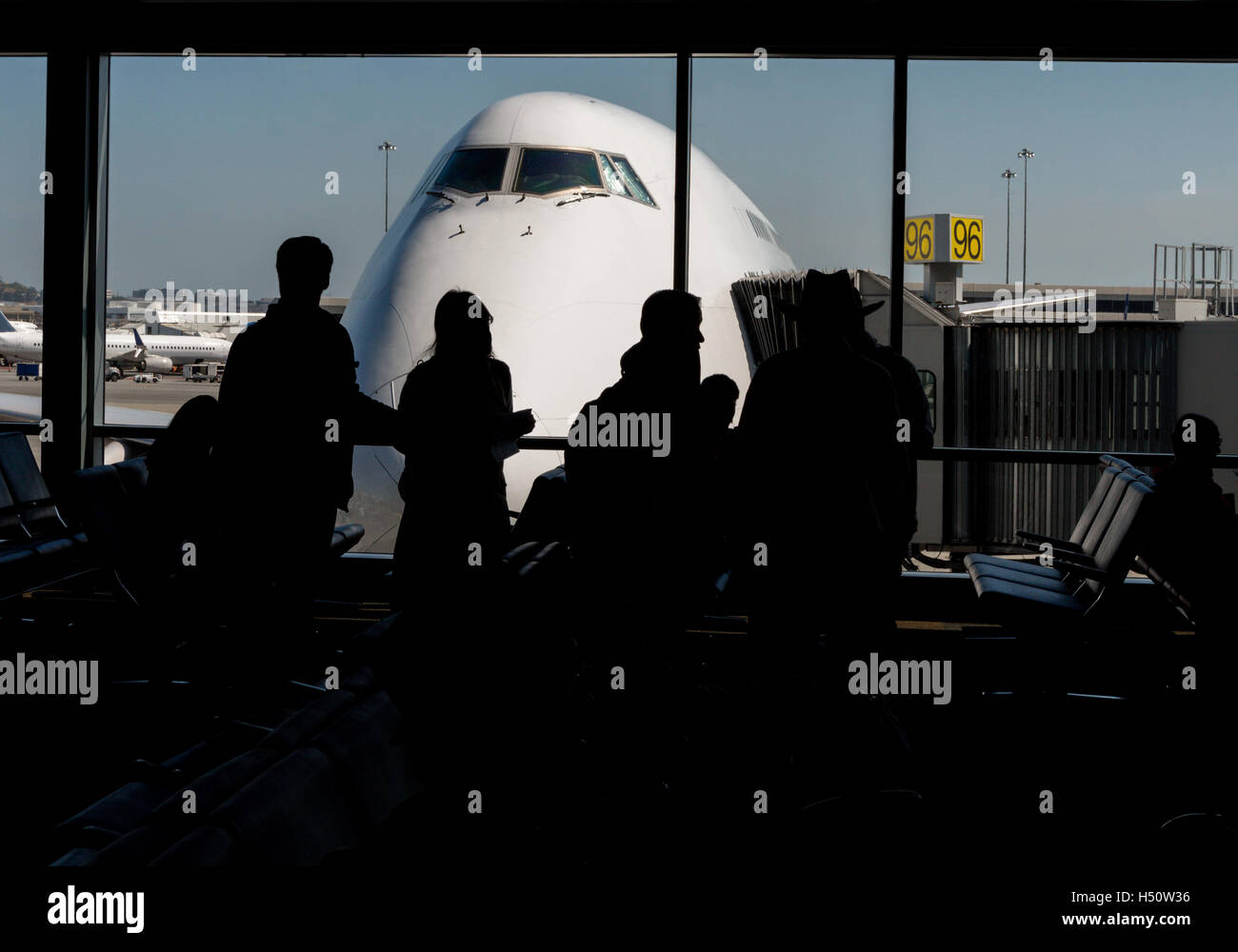 Silhouette di passeggeri in attesa all'aeroporto gate con il naso di un aereo al di fuori dell'aeroporto asfalto. Foto Stock