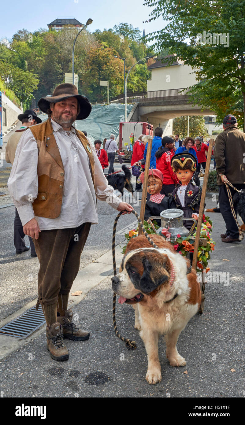 Uomo in abito tradizionale con un san Bernardo cane, la preparazione per le Retour des Alpages festival. Annecy, Alta Savoia, Francia. Foto Stock