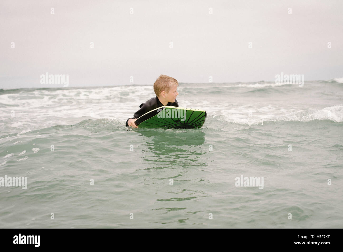 Ragazzo biondo bodyboarding nell'oceano. Foto Stock