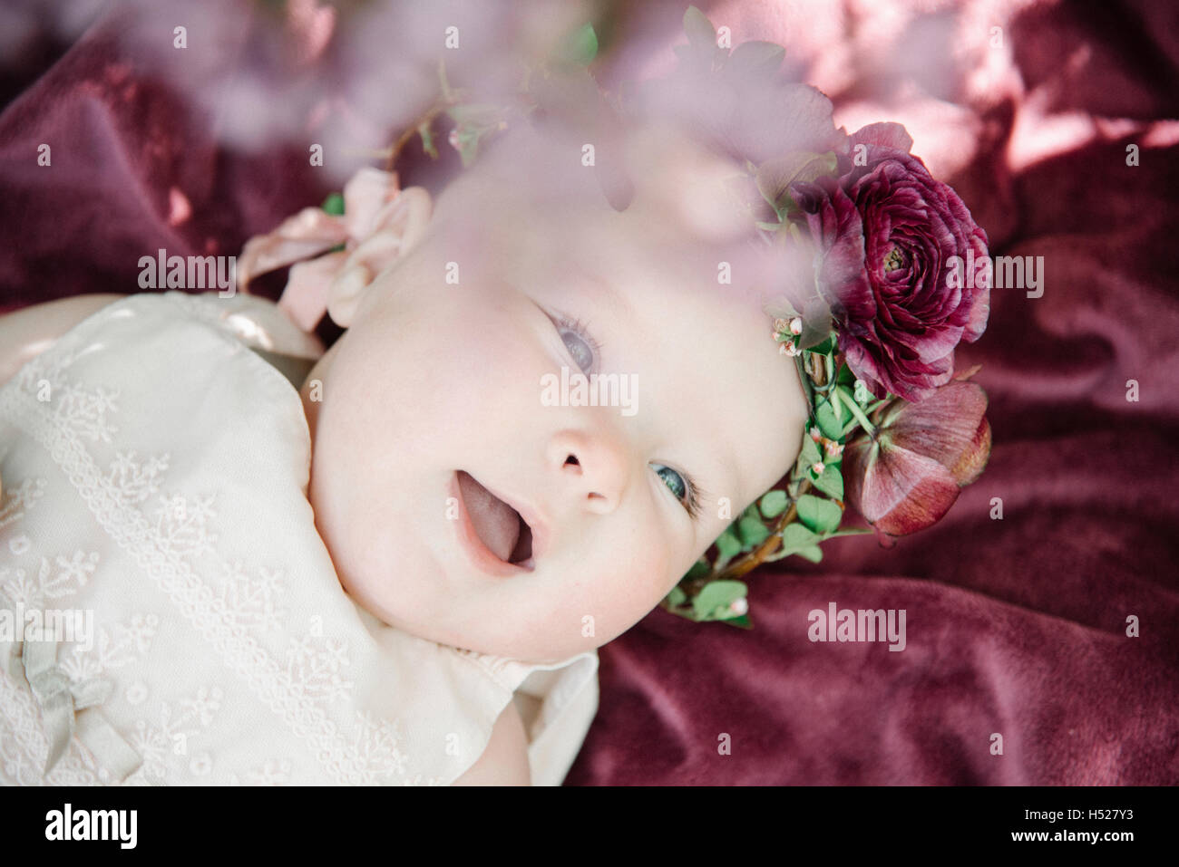 Ritratto di un sorridente bambina con una ghirlanda di fiori sulla sua testa. Foto Stock