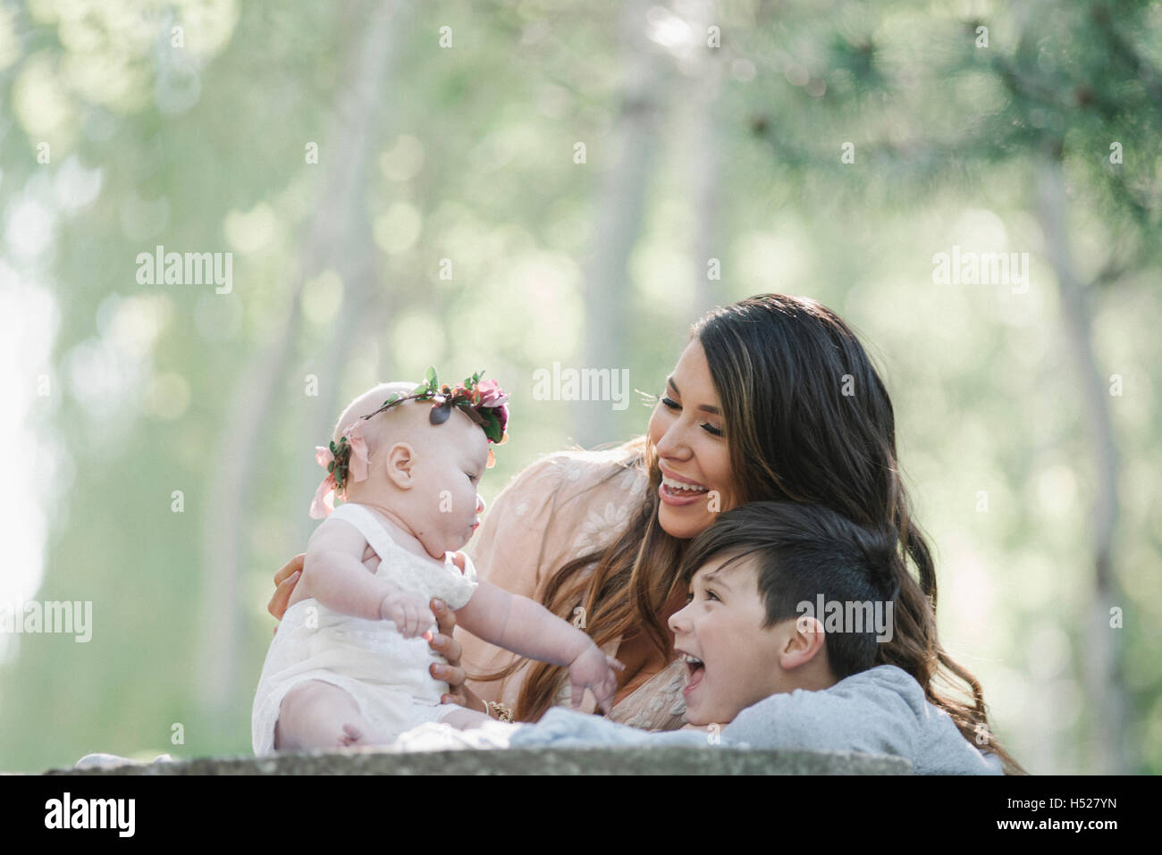 Ritratto di una madre sorridente, bambino e bambina con una ghirlanda di fiori sulla sua testa. Foto Stock