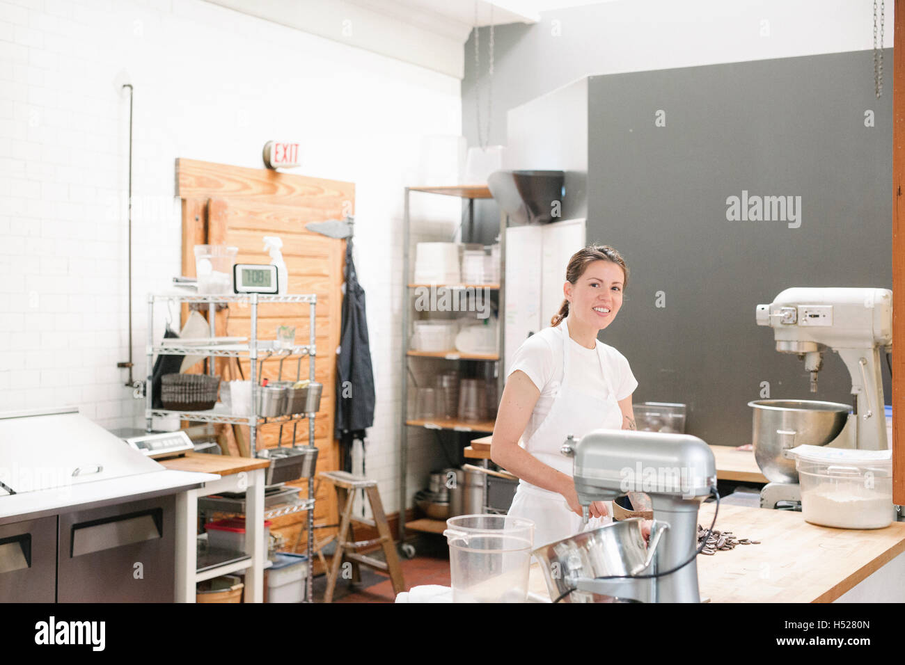 Donna che indossa un grembiule bianco in corrispondenza di un banco di lavoro in una panetteria. Foto Stock
