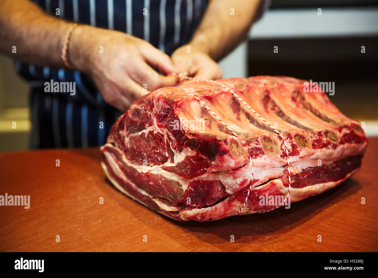 Butcher preparare un grande pezzo di carne di manzo in un butcherer's shop. Foto Stock
