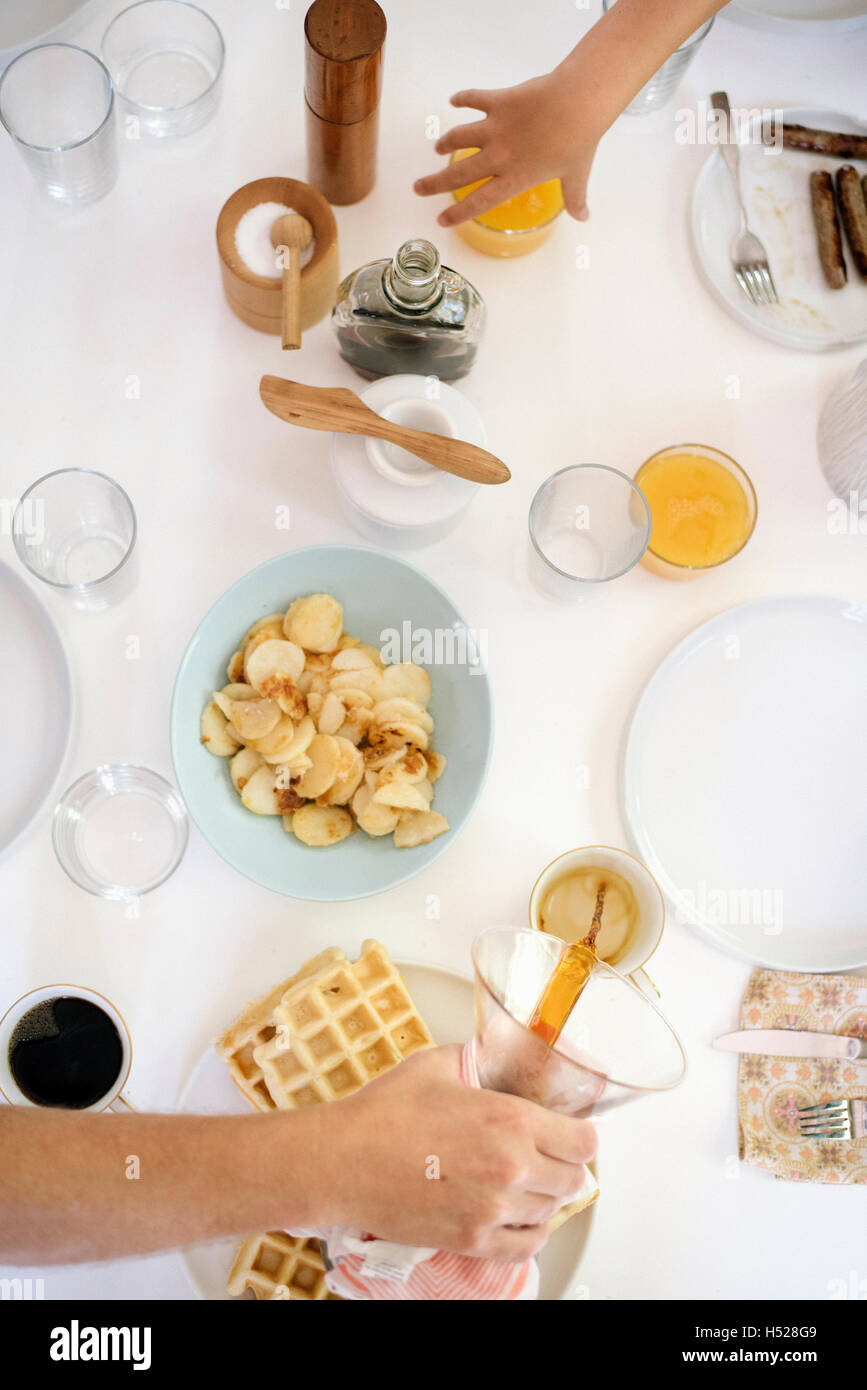 Elevato angolo di visione di un tavolo per la colazione, waffle, patate fritte, caffè e succo di frutta. Foto Stock