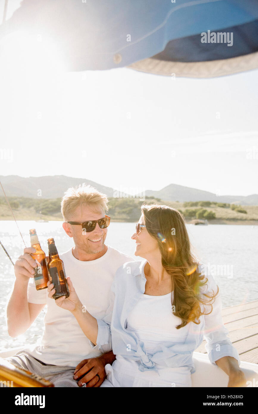 Un uomo e una donna su una imbarcazione a vela, avente un drink. Foto Stock