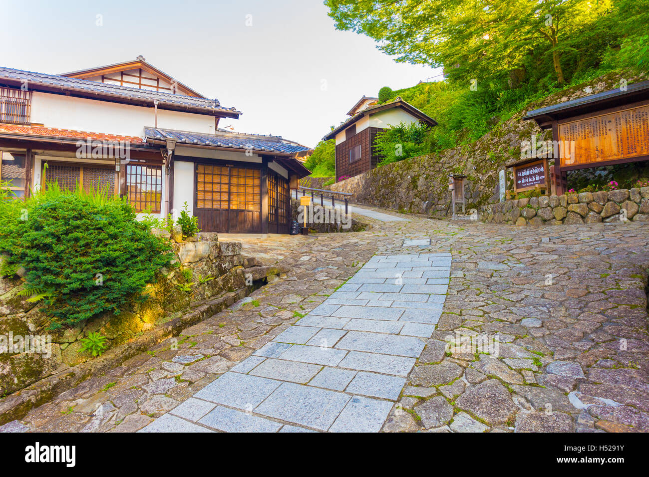 Ristrutturato edifici in legno su inclinato collinare percorso di pietra conduce all ingresso della città di Magome sulla antica Magome-Tsumago di Nakasendo Foto Stock