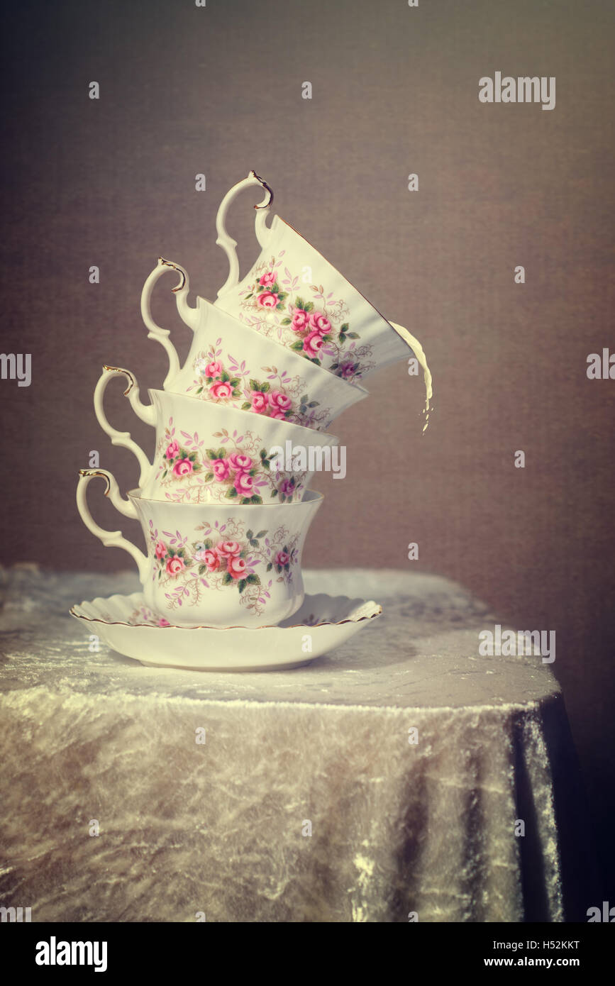 Pila di inclinato teacups vintage con latte fuoriuscita Foto Stock