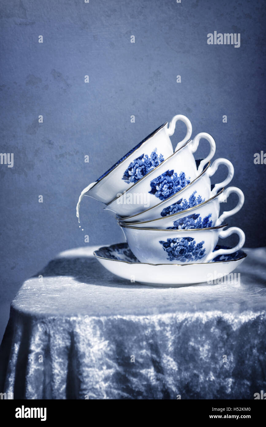 Pila di pretty blu e bianco teacups vintage con fuoriuscita di latte Foto Stock