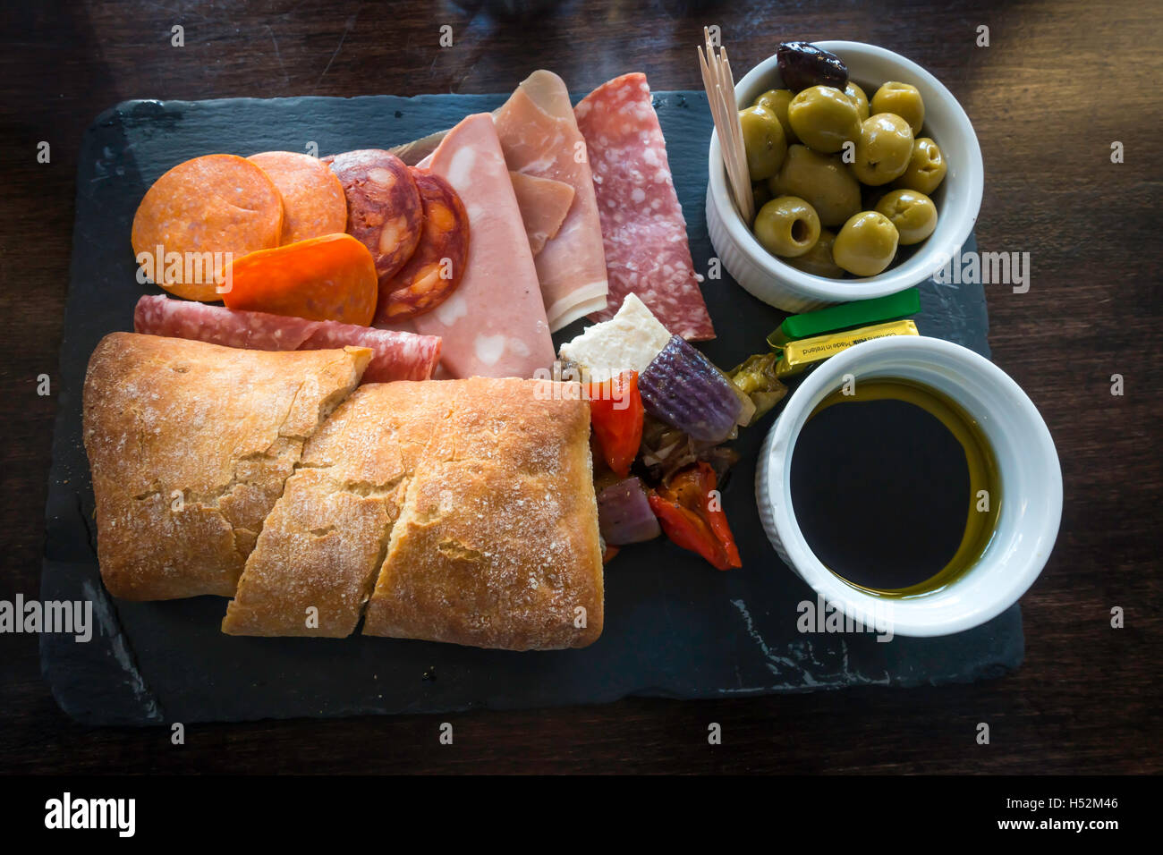 Ora di pranzo snack pasto deli platter affettati e formaggio Feta Ciabatta pane olio di oliva aceto balsamico cipolle e olive Foto Stock